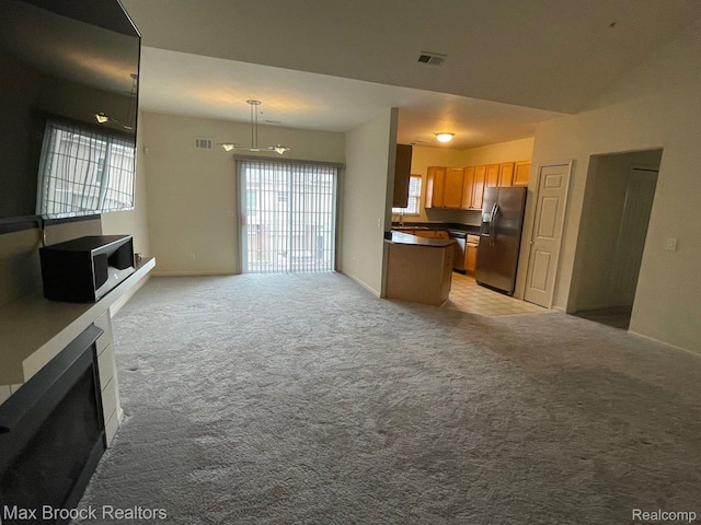 16211 Addington Dr Unit 192, Commerce Twp, MI 48390 - kitchen featuring stainless steel appliances, open floor plan, dark countertops, light colored carpet, and a fireplace