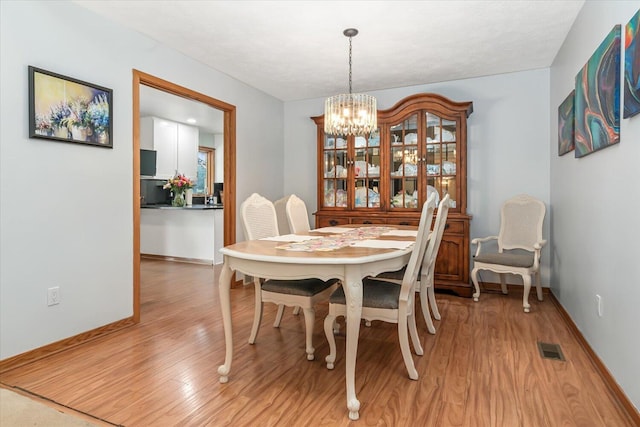 6767 Knollview Dr, Hudsonville, MI 49426 - dining room with a chandelier, light wood-type flooring, and baseboards