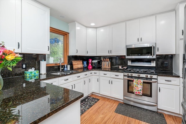 6767 Knollview Dr, Hudsonville, MI 49426 - kitchen with appliances with stainless steel finishes, a sink, light wood finished floors, white cabinets, and tasteful backsplash