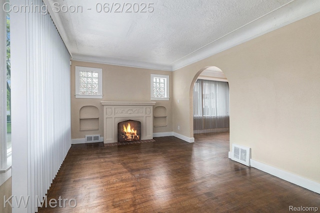 5025 Somerset Ave, Detroit, MI 48224 - unfurnished living room featuring arched walkways, a fireplace with flush hearth, a textured ceiling, healthy amount of natural light, and dark wood-style flooring