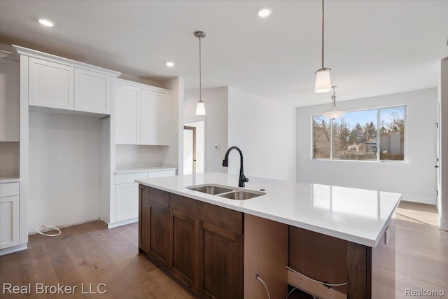 35704 Addison Dr, New Baltimore, MI 48047 - kitchen featuring a sink, white cabinets, light countertops, light wood-style flooring, and a center island with sink