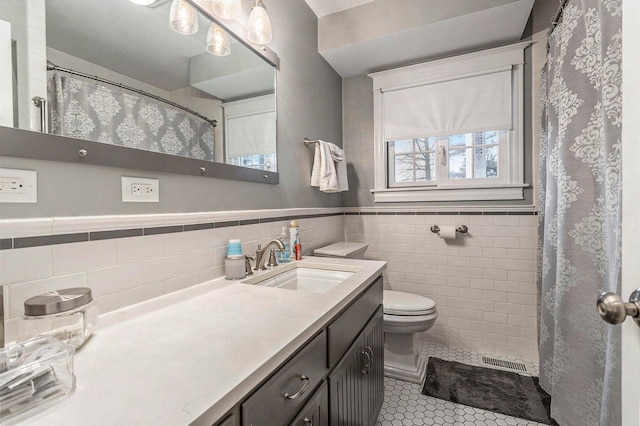 3313 Gethings Rd, Battle Creek, MI 49015 - bathroom with tile walls, tile patterned floors, vanity, toilet, and a wainscoted wall