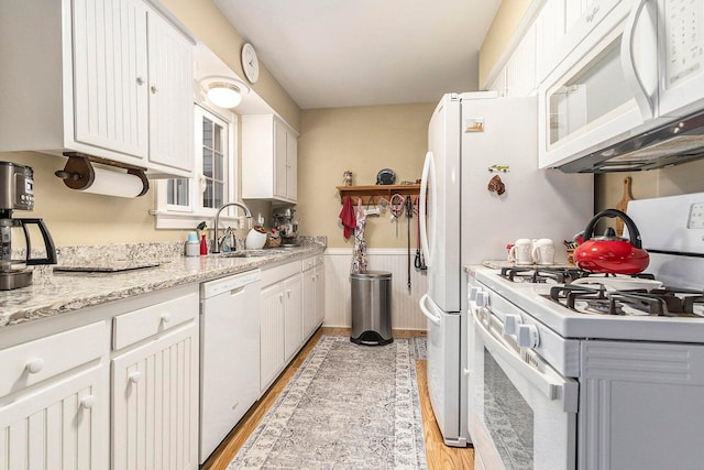 3313 Gethings Rd, Battle Creek, MI 49015 - kitchen with white appliances, a sink, light wood-style floors, a wainscoted wall, and white cabinetry