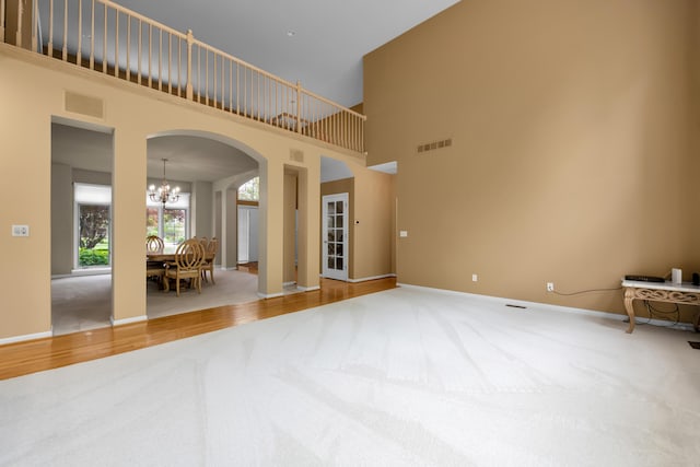 482 Torrington Dr W, Canton, MI 48188 - spare room featuring carpet flooring, arched walkways, a chandelier, a high ceiling, and baseboards