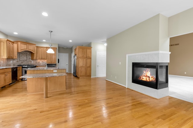 482 Torrington Dr W, Canton, MI 48188 - kitchen featuring appliances with stainless steel finishes, a center island with sink, a sink, decorative backsplash, and light wood-type flooring