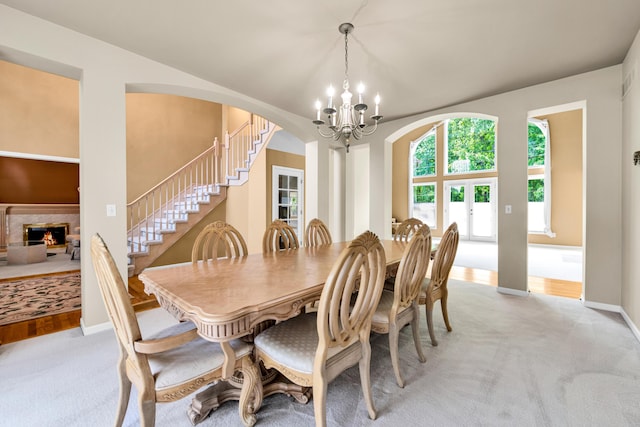 482 Torrington Dr W, Canton, MI 48188 - dining space with stairway, a chandelier, light colored carpet, a fireplace, and arched walkways