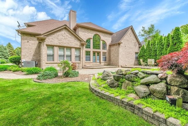 482 Torrington Dr W, Canton, MI 48188 - rear view of house with brick siding, a chimney, a yard, a patio, and central air condition unit