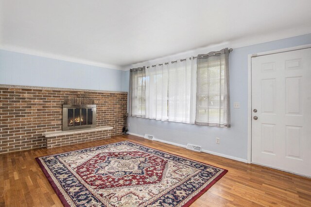 2013 Cumberland St, Kalamazoo, MI 49006 - unfurnished living room with wood finished floors, a brick fireplace, and baseboards