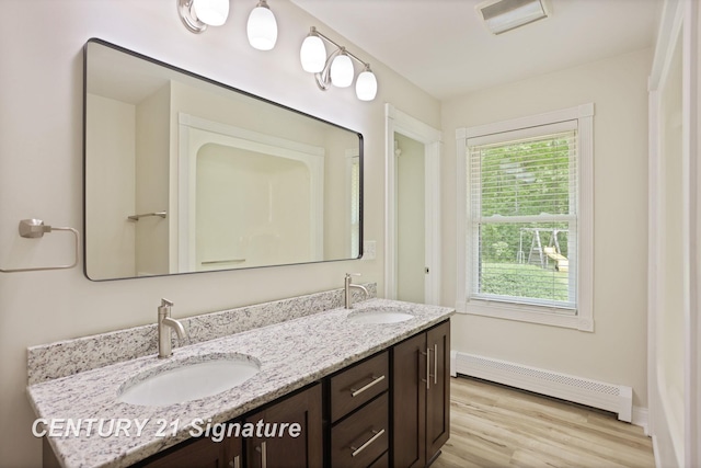 4769 S Fordney Rd, Hemlock, MI 48626 - full bathroom featuring a baseboard heating unit, double vanity, wood finished floors, and baseboards