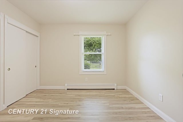 4769 S Fordney Rd, Hemlock, MI 48626 - unfurnished bedroom with baseboard heating, light wood-type flooring, a closet, and baseboards