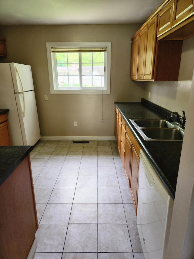 179 W State St, Coldwater, MI 49036 - kitchen featuring white appliances, dark countertops, light tile patterned floors, and brown cabinetry