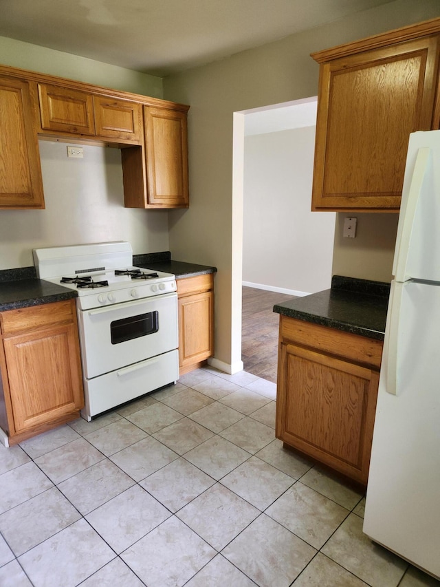 179 W State St, Coldwater, MI 49036 - kitchen featuring white appliances, dark countertops, brown cabinets, and light tile patterned floors