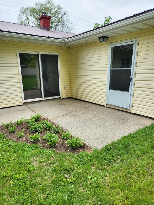 179 W State St, Coldwater, MI 49036 - back of property with a patio area, a metal roof, a chimney, and a lawn