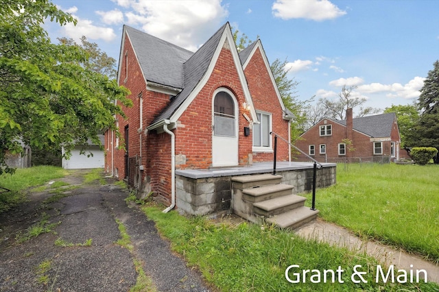 19250 Charest St, Detroit, MI 48234 - tudor-style house featuring brick siding, a shingled roof, an outdoor structure, and asphalt driveway