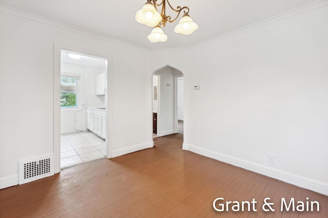 19250 Charest St, Detroit, MI 48234 - empty room with arched walkways, a chandelier, light wood-style flooring, ornamental molding, and baseboards