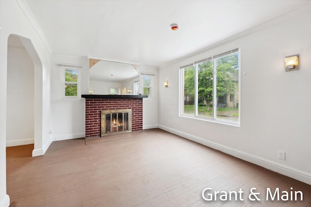 19250 Charest St, Detroit, MI 48234 - unfurnished living room with ornamental molding, wood-type flooring, baseboards, a fireplace, and arched walkways