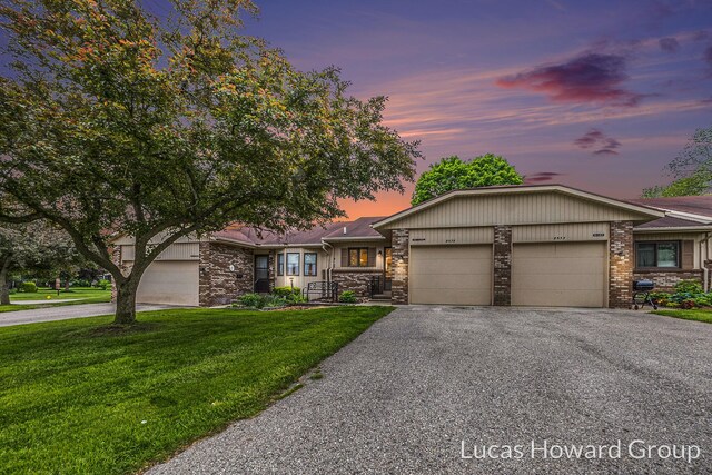 8535 Elkwood Dr SW, Byron Center, MI 49315 - view of front of house featuring a garage, asphalt driveway, a yard, and stone siding