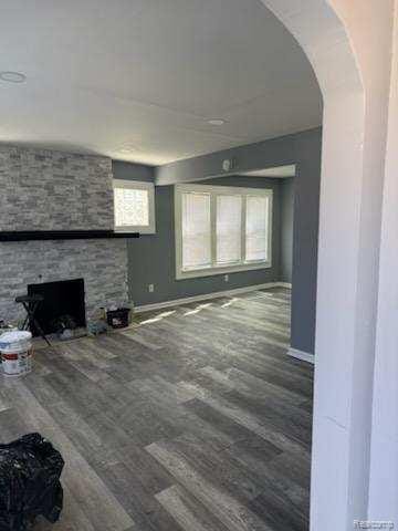 14557 Strathmoor St, Detroit, MI 48227 - unfurnished living room with wood finished floors, baseboards, a fireplace, and arched walkways