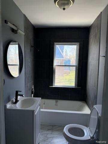 14557 Strathmoor St, Detroit, MI 48227 - full bathroom with toilet, vanity, marble look tile flooring, and shower / washtub combination