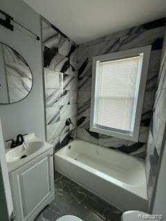 14557 Strathmoor St, Detroit, MI 48227 - bathroom featuring toilet, vanity, marble finish floors, and tub / shower combination