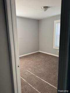 14557 Strathmoor St, Detroit, MI 48227 - empty room featuring baseboards and dark carpet