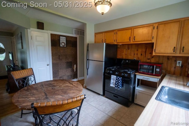 29974 Tamarack Dr, Flat Rock, MI 48134 - kitchen featuring black gas stove, a sink, light countertops, freestanding refrigerator, and brown cabinets