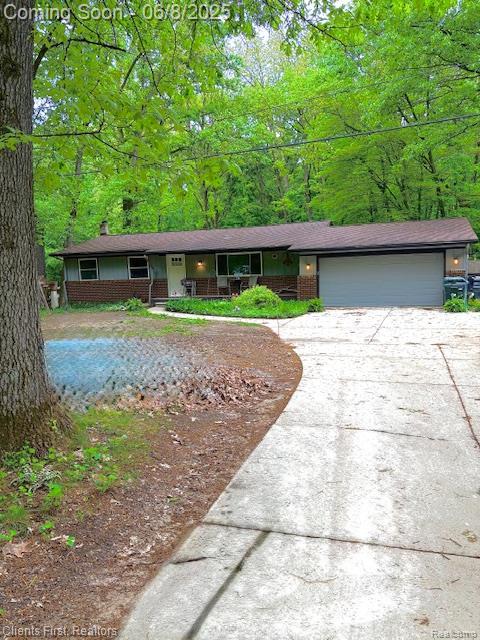 5844 Crandall Rd, Howell, MI 48855 - view of front of house with driveway, covered porch, an attached garage, and brick siding
