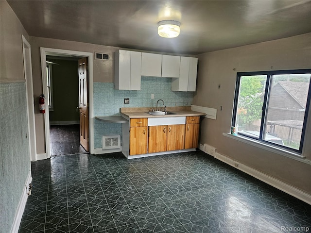 4634 8th St, Ecorse, MI 48229 - kitchen with a sink, baseboards, light countertops, tasteful backsplash, and white cabinets