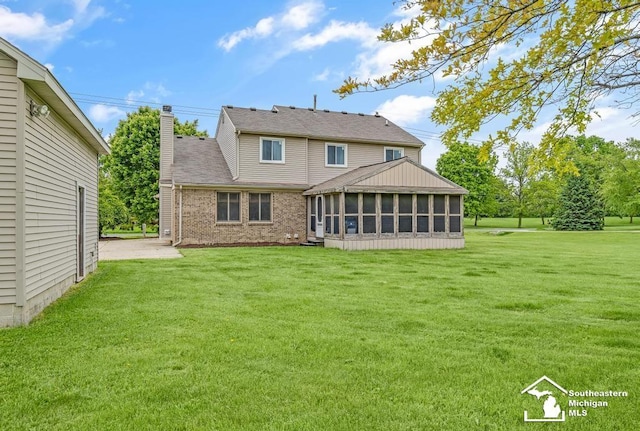 177 W Willis Rd, Saline, MI 48176 - rear view of house with a sunroom, a chimney, a yard, and brick siding