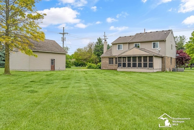 177 W Willis Rd, Saline, MI 48176 - back of property featuring a chimney, a sunroom, a yard, and brick siding