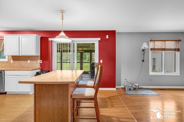 177 W Willis Rd, Saline, MI 48176 - kitchen featuring white cabinetry, light wood-style flooring, backsplash, dishwasher, and a breakfast bar