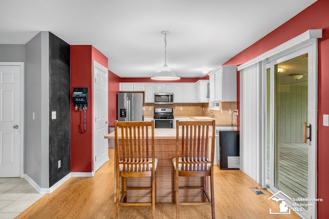 177 W Willis Rd, Saline, MI 48176 - kitchen with appliances with stainless steel finishes, light countertops, white cabinetry, decorative backsplash, and light wood-type flooring