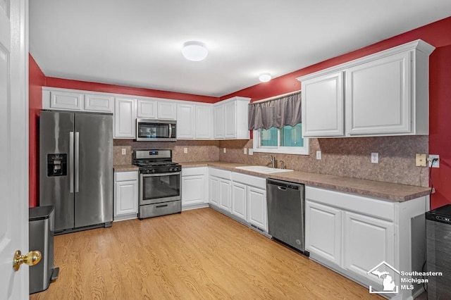 177 W Willis Rd, Saline, MI 48176 - kitchen featuring appliances with stainless steel finishes, a sink, light wood-style floors, and white cabinetry