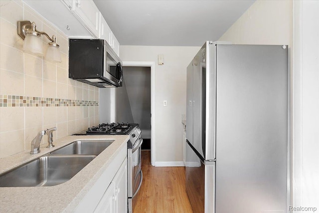 22865 Lakeshore Dr, Saint Clair Shores, MI 48080 - kitchen with appliances with stainless steel finishes, a sink, decorative backsplash, light wood-style flooring, and white cabinetry