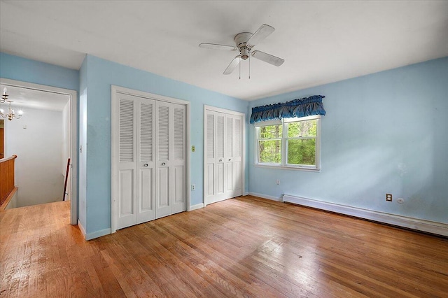 2100 Delhi W, Ann Arbor, MI 48103 - unfurnished bedroom with two closets, wood finished floors, a chandelier, baseboards, and a baseboard heating unit