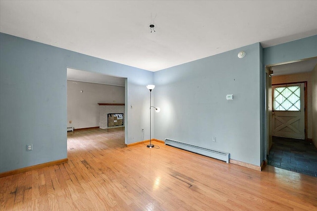 2100 Delhi W, Ann Arbor, MI 48103 - spare room featuring a baseboard heating unit, wood finished floors, baseboards, and a fireplace