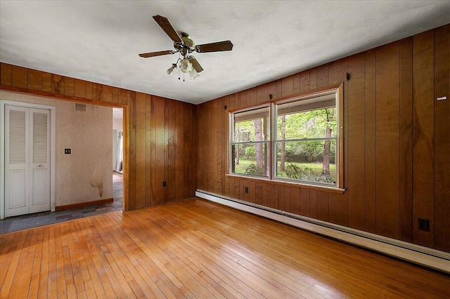 2100 Delhi W, Ann Arbor, MI 48103 - unfurnished room featuring a baseboard heating unit, hardwood / wood-style floors, wood walls, and ceiling fan