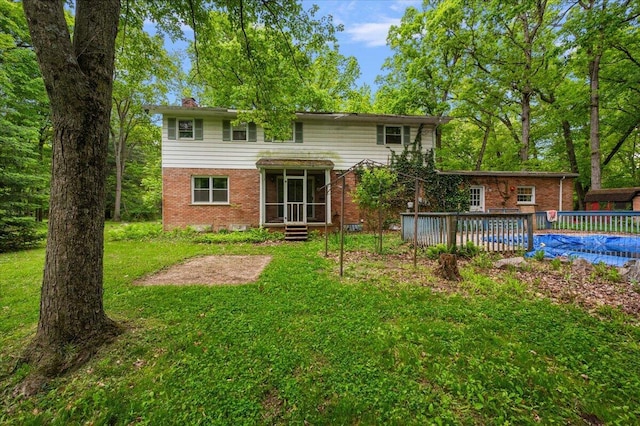 2100 Delhi W, Ann Arbor, MI 48103 - rear view of property featuring brick siding, a yard, a chimney, and a wooden deck