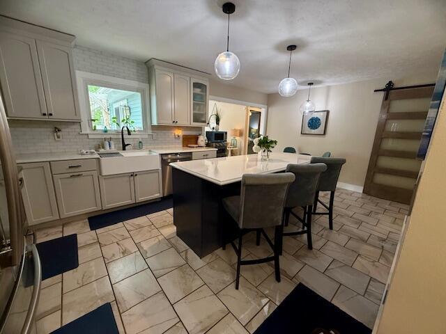 307 W 30th St, Holland, MI 49423 - kitchen featuring a sink, stainless steel appliances, a kitchen bar, tasteful backsplash, and a kitchen island