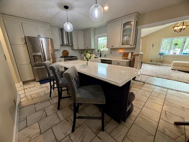 307 W 30th St, Holland, MI 49423 - kitchen with wall chimney range hood, stainless steel appliances, light marble finish flooring, light countertops, and decorative backsplash