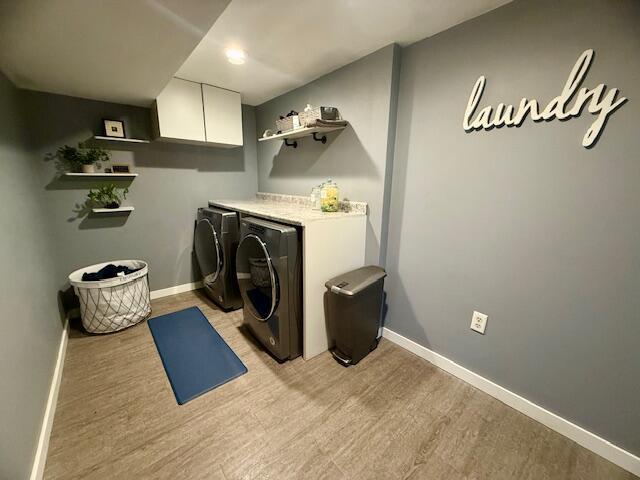 307 W 30th St, Holland, MI 49423 - laundry area featuring washer and dryer, cabinet space, light wood-style flooring, and baseboards