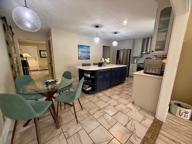 307 W 30th St, Holland, MI 49423 - kitchen with stainless steel appliances, light countertops, a kitchen island, glass insert cabinets, and light marble finish floors