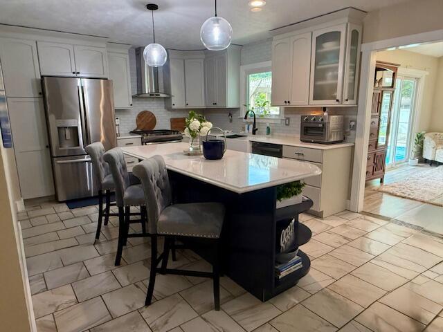 307 W 30th St, Holland, MI 49423 - kitchen featuring stainless steel refrigerator with ice dispenser, wall chimney exhaust hood, stove, light countertops, and light marble finish flooring