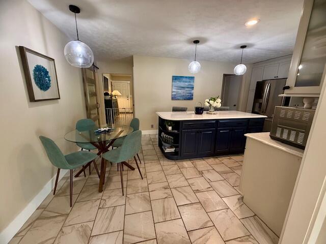 307 W 30th St, Holland, MI 49423 - kitchen featuring baseboards, light countertops, a kitchen island, stainless steel refrigerator with ice dispenser, and light marble finish floors
