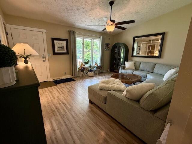 307 W 30th St, Holland, MI 49423 - living room featuring a textured ceiling, ceiling fan, light wood-type flooring, baseboards, and vaulted ceiling
