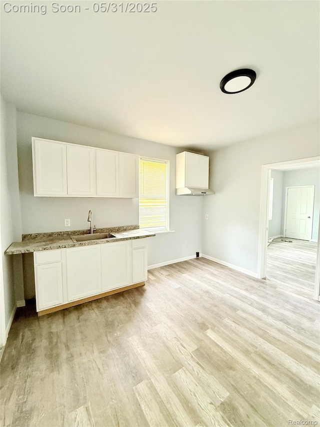 3648 Mack Ave, Hamtramck, MI 48207 - kitchen with a sink, white cabinetry, baseboards, light wood-type flooring, and light stone counters