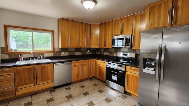 810 Division St, Adrian, MI 49221 - kitchen with stainless steel appliances, a sink, decorative backsplash, dark countertops, and brown cabinets