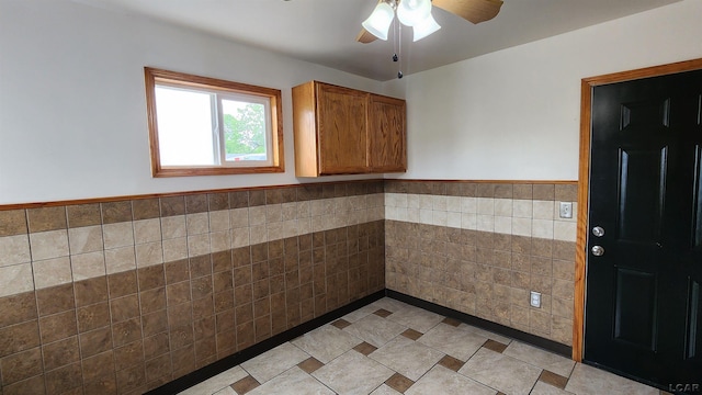 810 Division St, Adrian, MI 49221 - kitchen with tile walls, ceiling fan, a wainscoted wall, brown cabinetry, and dark countertops