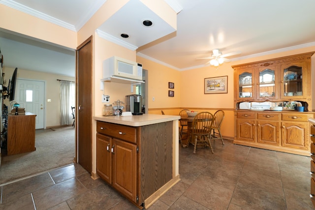 3624 Terhune Rd, Ann Arbor, MI 48104 - kitchen with ornamental molding, ceiling fan, brown cabinetry, dark carpet, and light countertops
