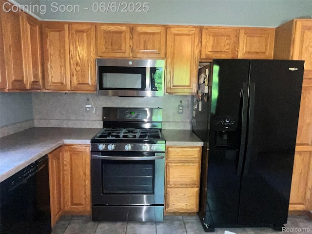 1379 Walter S Hall Dr, Lake Orion, MI 48362 - kitchen with black appliances, light tile patterned flooring, and brown cabinetry